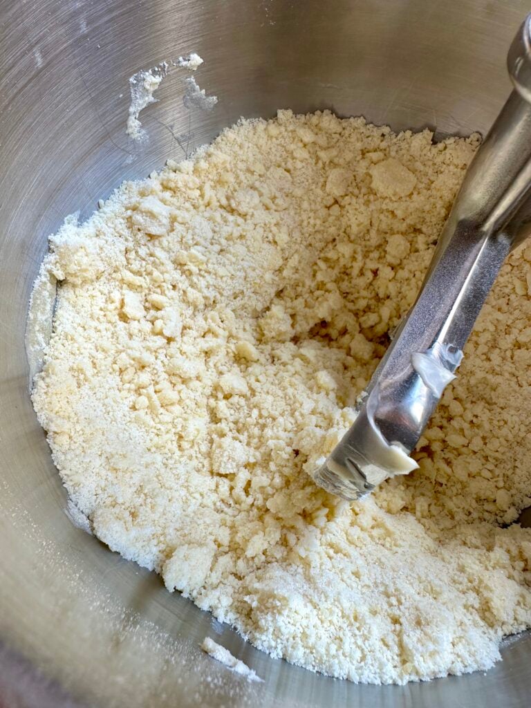 Reverse creaming butter into sugar and flour inside a stand mixer bowl.