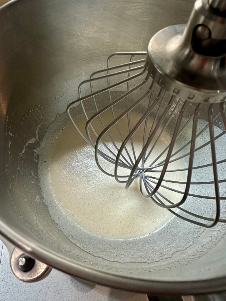 Bowl of liquid egg whites with a whisk attachment.