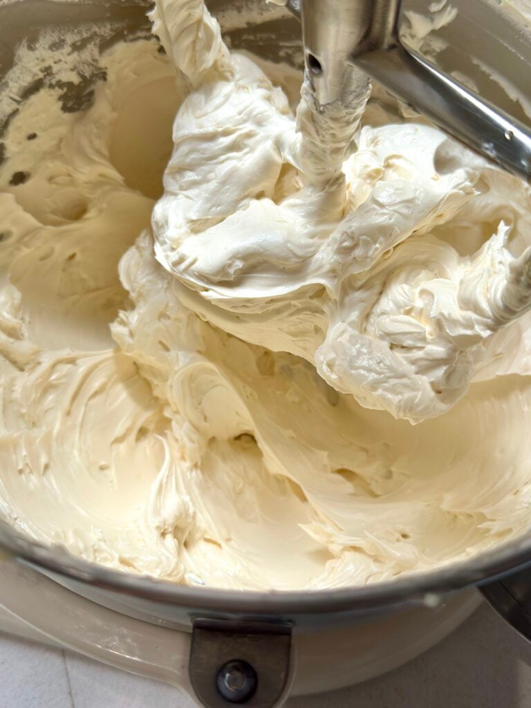 Buttercream frosting inside a stand mixing bowl with paddle attachment.