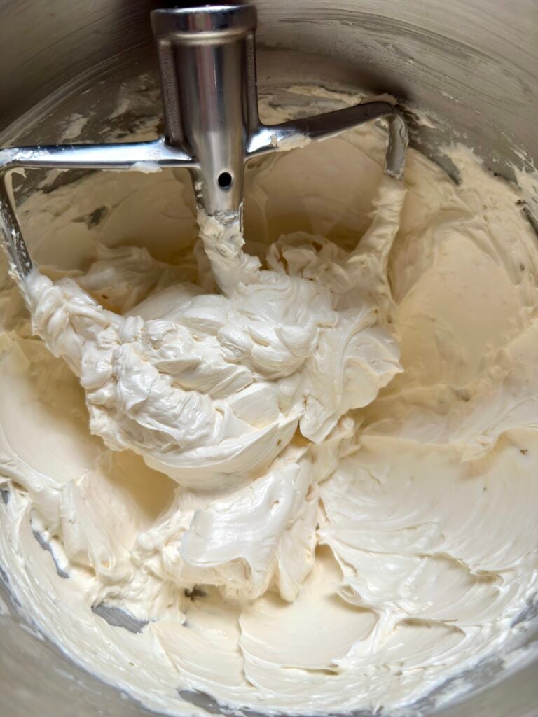 Honey buttercream in bowl with paddle attachment.