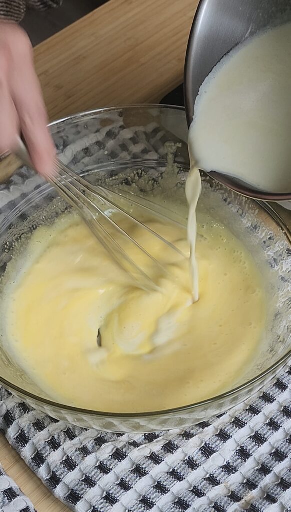 Tempering egg yolks with ot cream in a saucepan.
