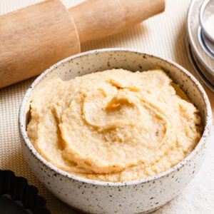 Bowl of French almond cream next to a rolling pin and tart pan.
