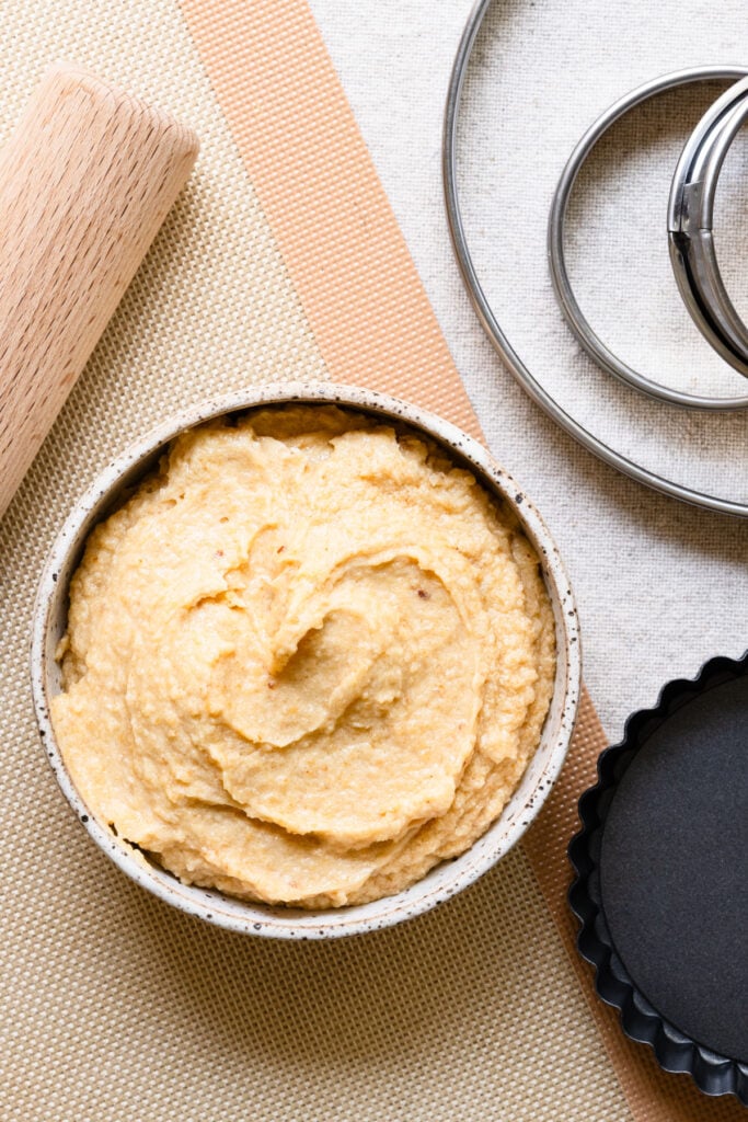 Overhead of French almond cream in a bowl next to baking supplies.