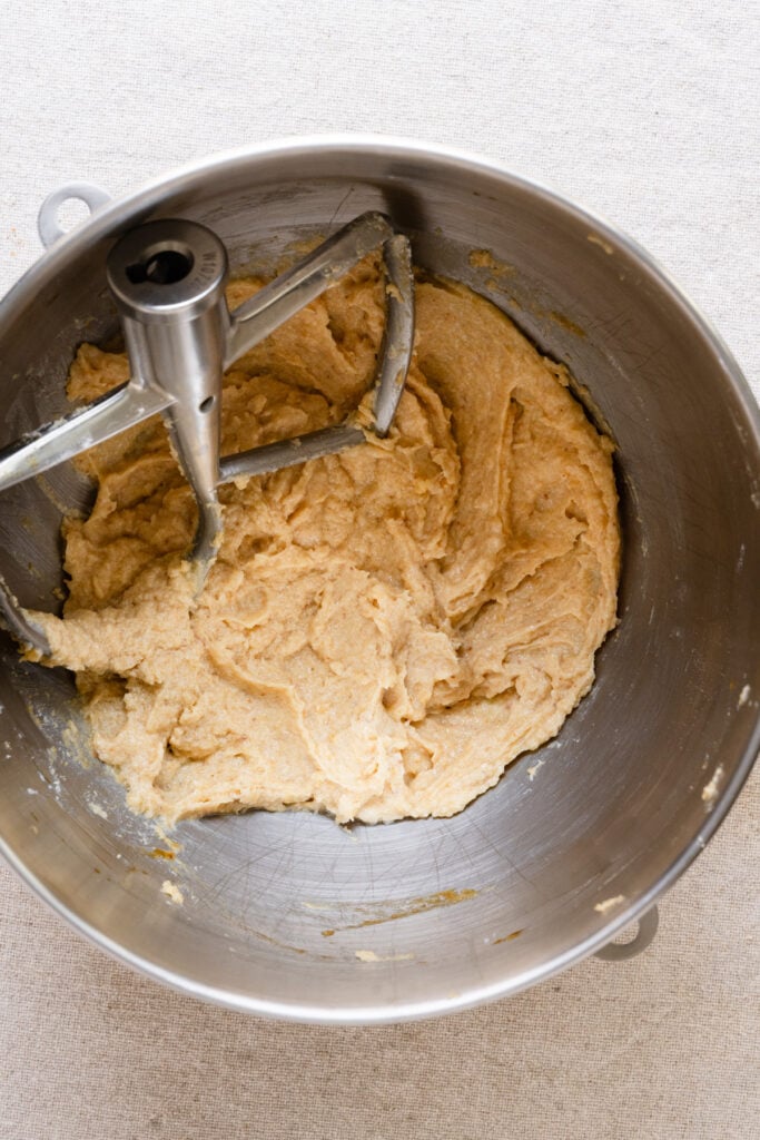 Almond cream inside the bowl of a stand mixer with paddle attachment.
