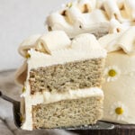 Slice of two layer banana cake being held on a pie server.