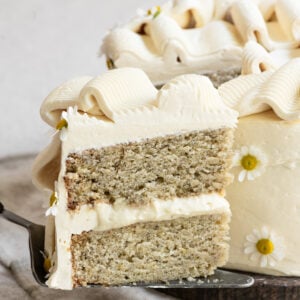 Slice of two layer banana cake being held on a pie server.