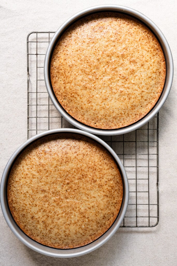 Overhead of wto pakes cakes in their pans on a cooling rack.