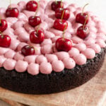 Chocolate cake topped with whipped cherry ganache frosting and fresh cherries.