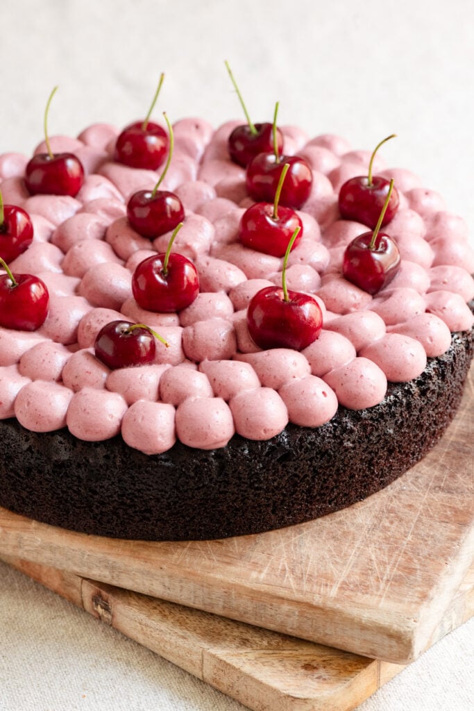 Chocolate cake topped with whipped cherry ganache frosting and fresh cherries.