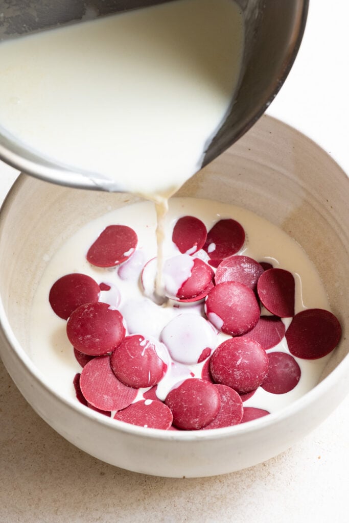 Cream being poured over raspberry chocolate in a bowl.