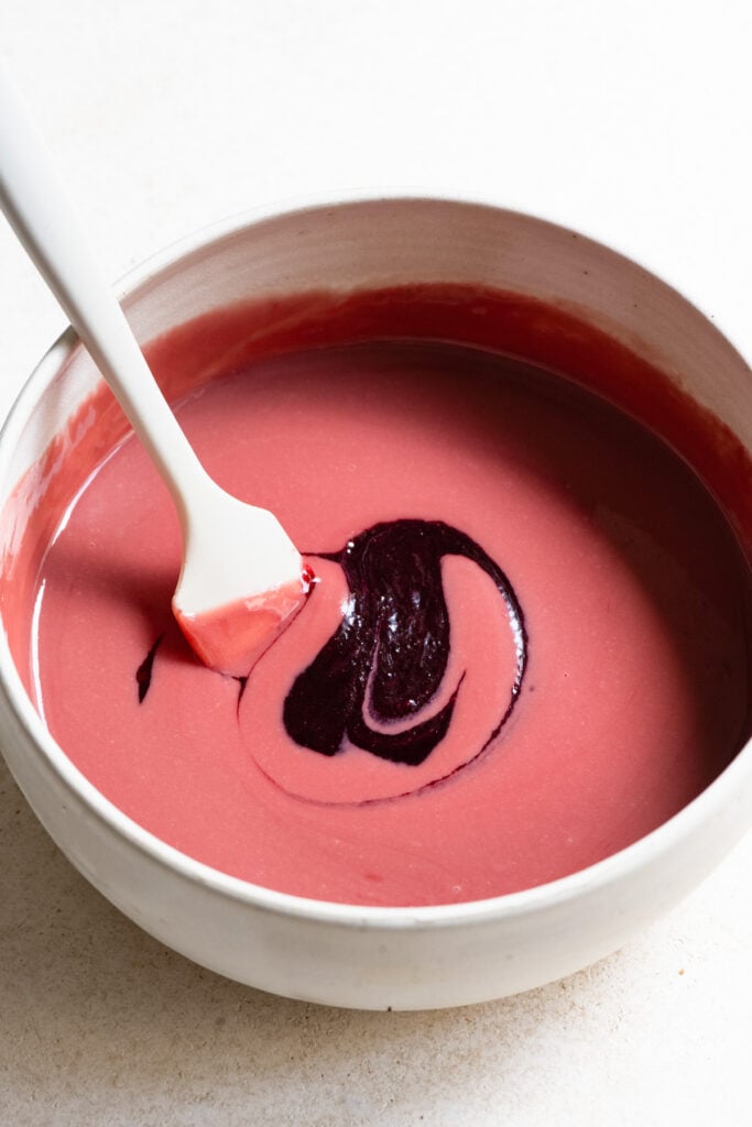 Cherry puree being stirred into melted raspberry chocolate.