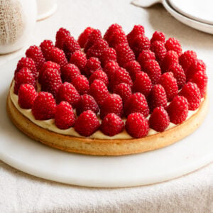 Raspberry french tart with a sweet crust on a table.