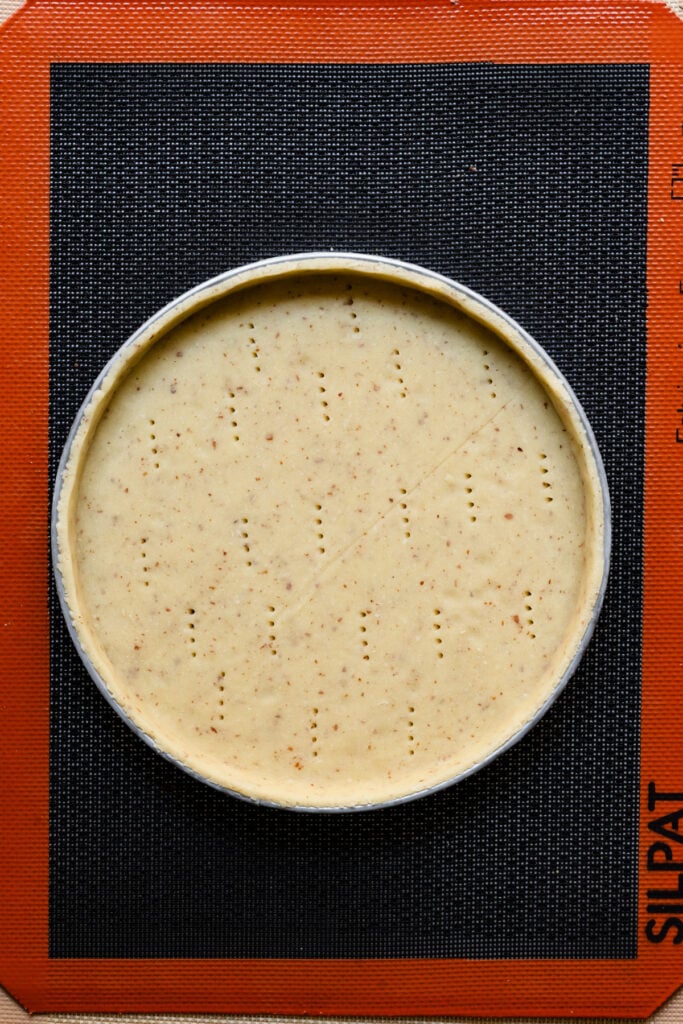 Overhead of tart dough lined pastry shell with fork pricks across the dough.