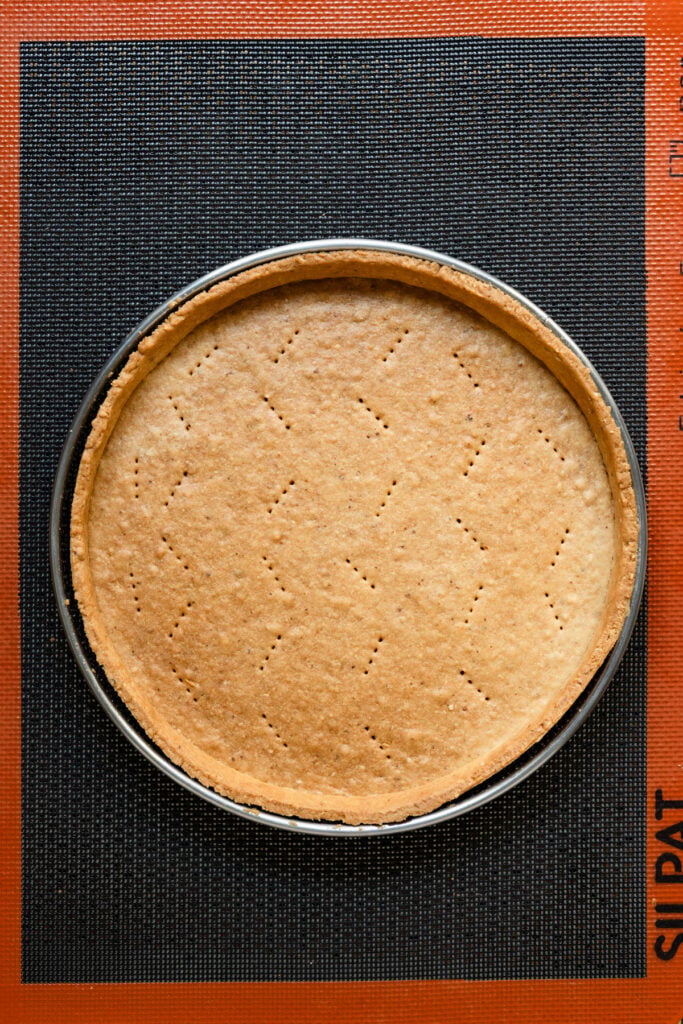 Overhead of blind baked tart shell on baking mat.