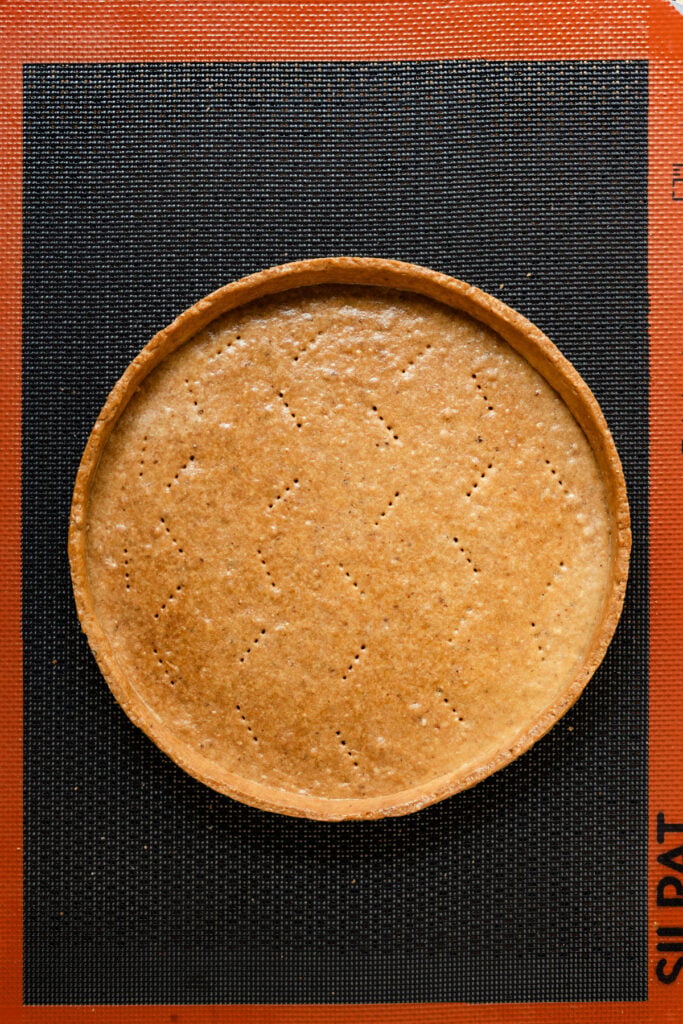 Overhead of a fully blind baked tart shell on a baking mat.