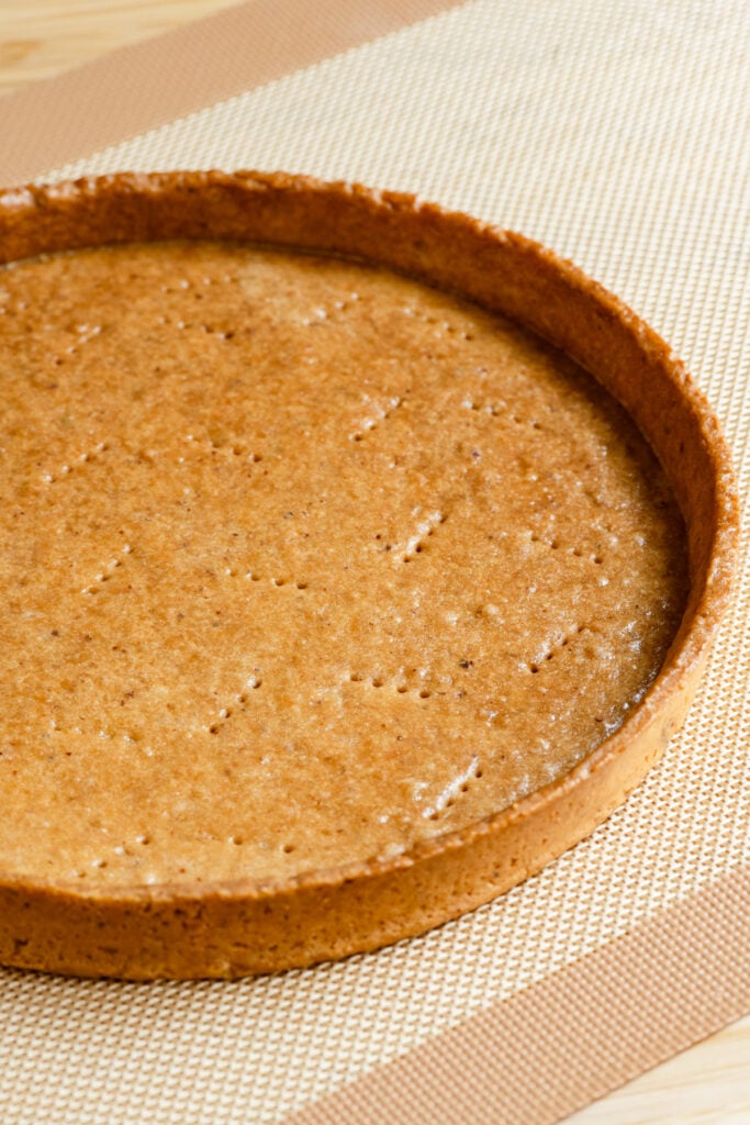 Baked pate sucree tart shell on a baking mat.