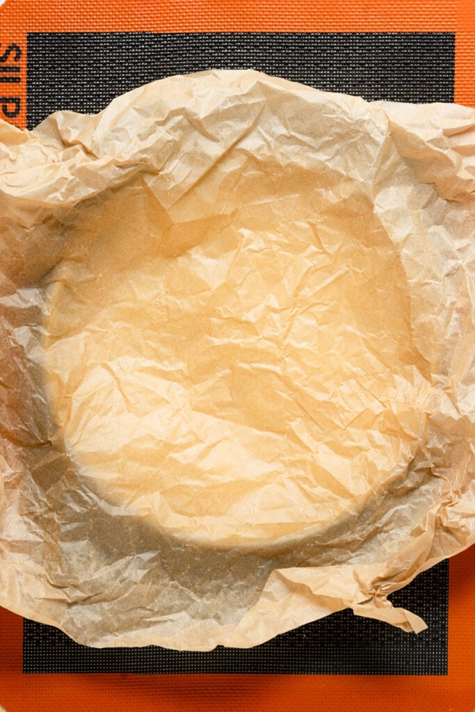 Overhead of a pastry lined tart shell covered with parchment paper.