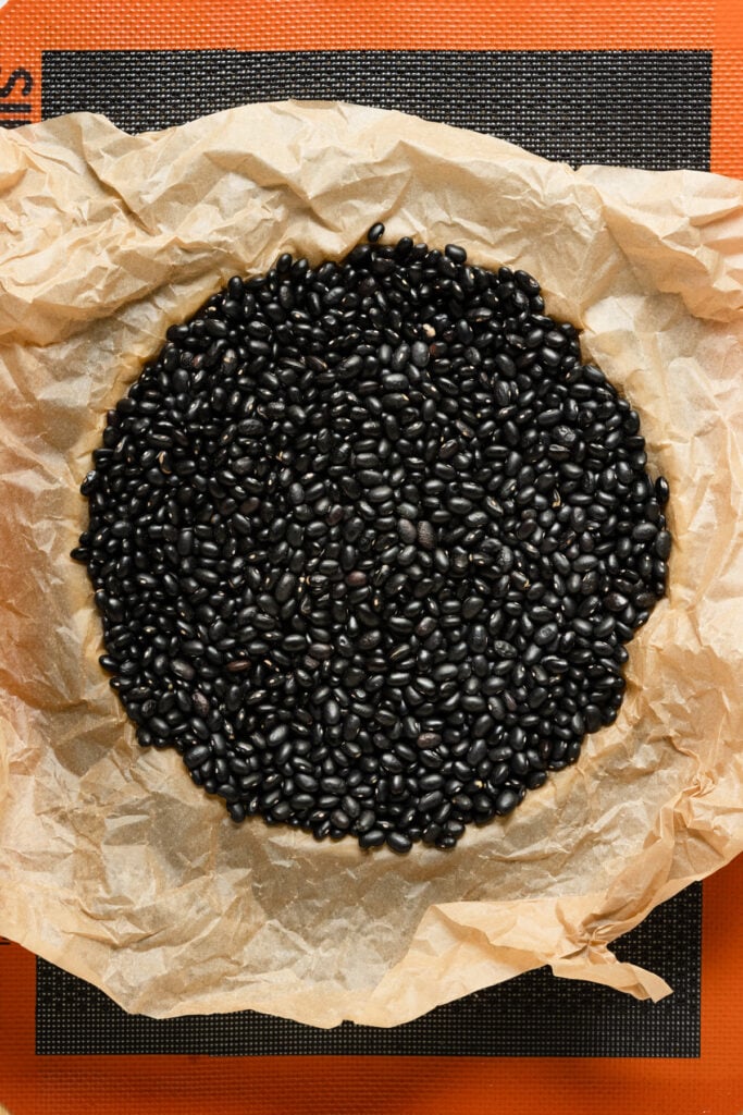 Overhead of a dough lined tart ring filled with parchment paper and dried black beans.