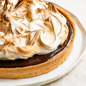 Closeup of a chocolate s'mores tart topped with toasted marshmallow meringue.