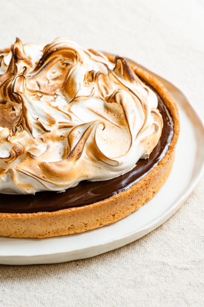Closeup of a chocolate s'mores tart topped with toasted marshmallow meringue.