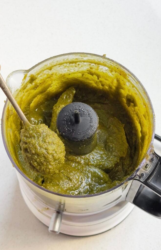 Roasted pistachio pastes scooped by a spoon from a blender.