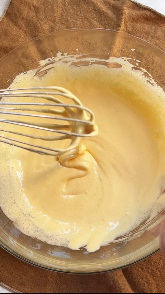 Whipped egg yolks and sugar in a bowl with a whisk.