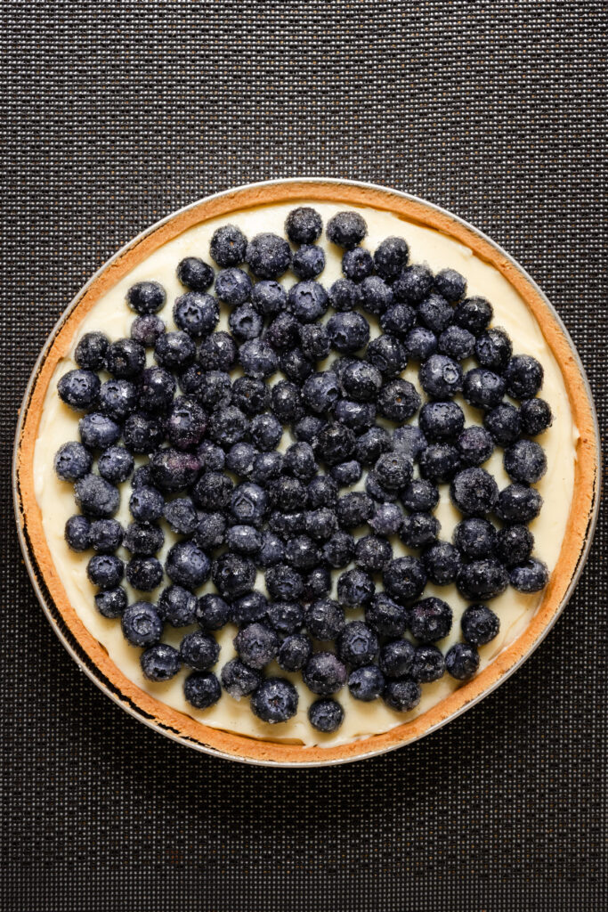 Overhead of an. unbaked blueberry topped flan tart.