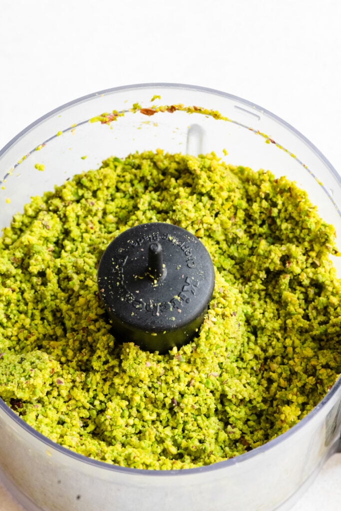 Food processor filled with chopped pistachios.