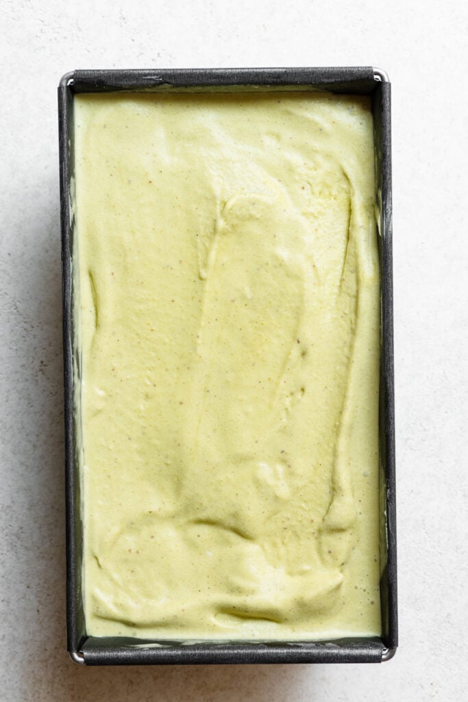 Overhead of a metal loaf pan filled with pistachio ice cream.