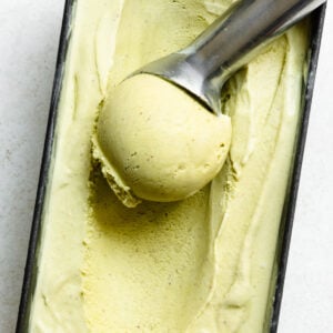Overhead of a scoop of pistachio ice cream in a container of ice cream.
