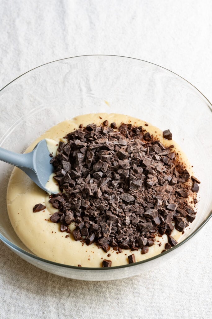 Chopped chocolate on top of pastry cream in a bowl.