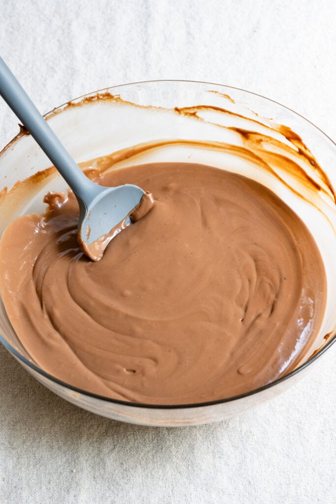 Chocolate pastry cream in a glass mixing bowl with a spatula.