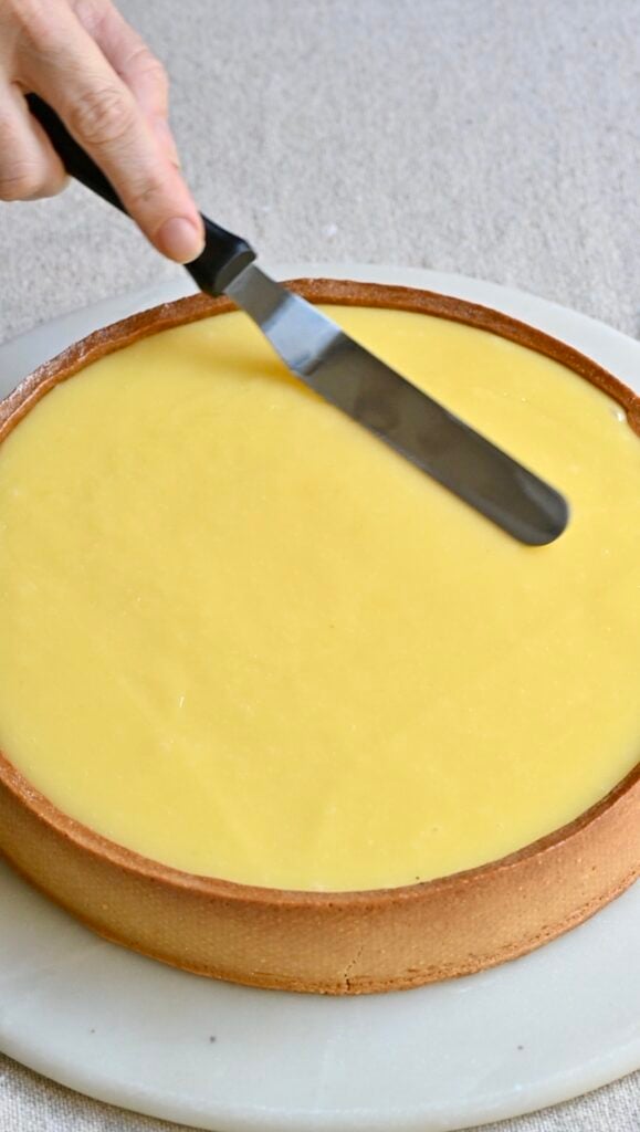 Spatula leveling the top of a lemon tart.