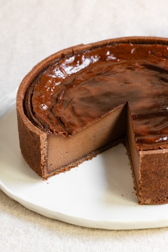 French chocolate flan on a plate with a slice missing.