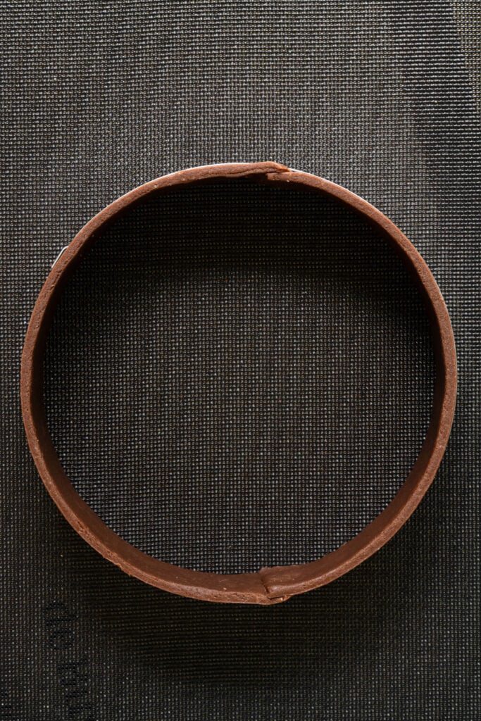 Tart ring lined with chocolate pastry dough around the sides.