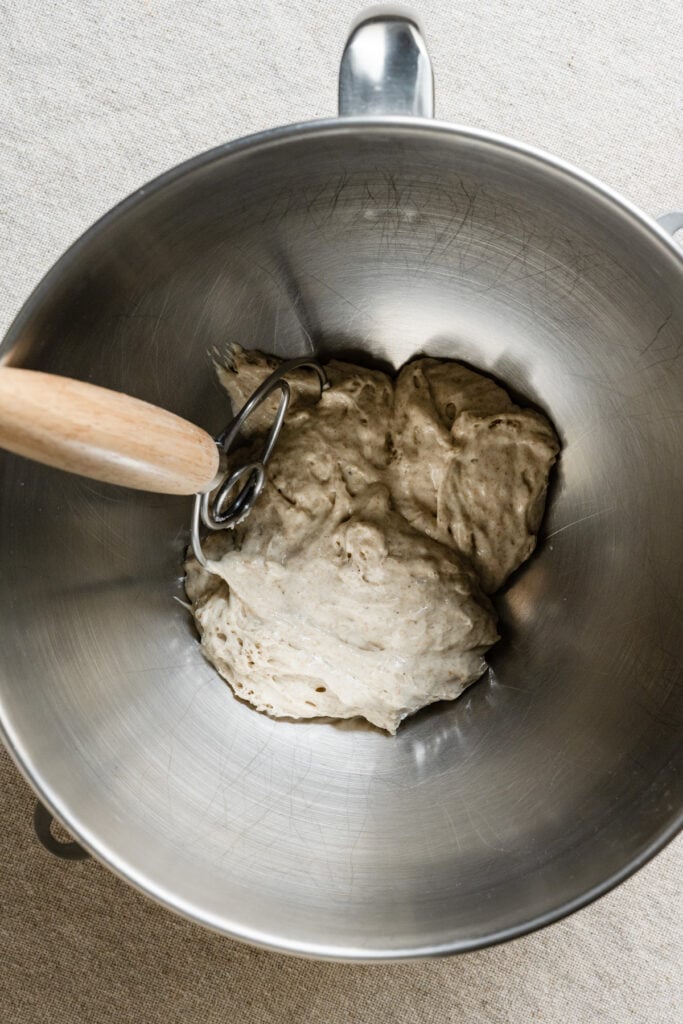 overhead of sourdough starter in a mixing bowl with a dough whisk.