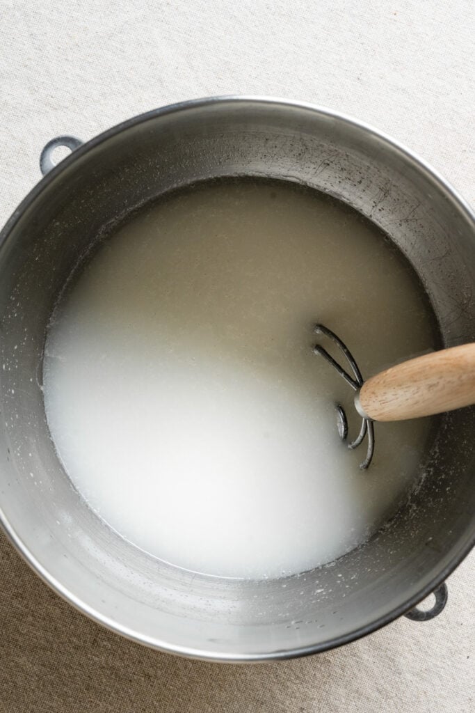 Overhead of sourdough starter and water mixed in a bowl.