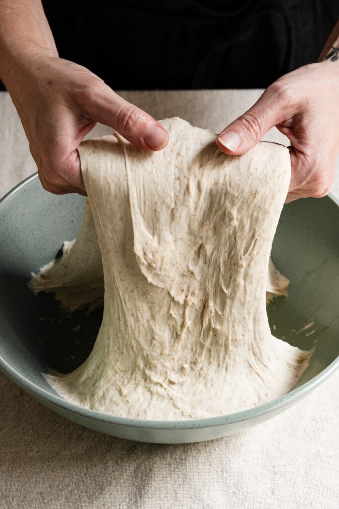 Two hands lifting dough from a bowl.