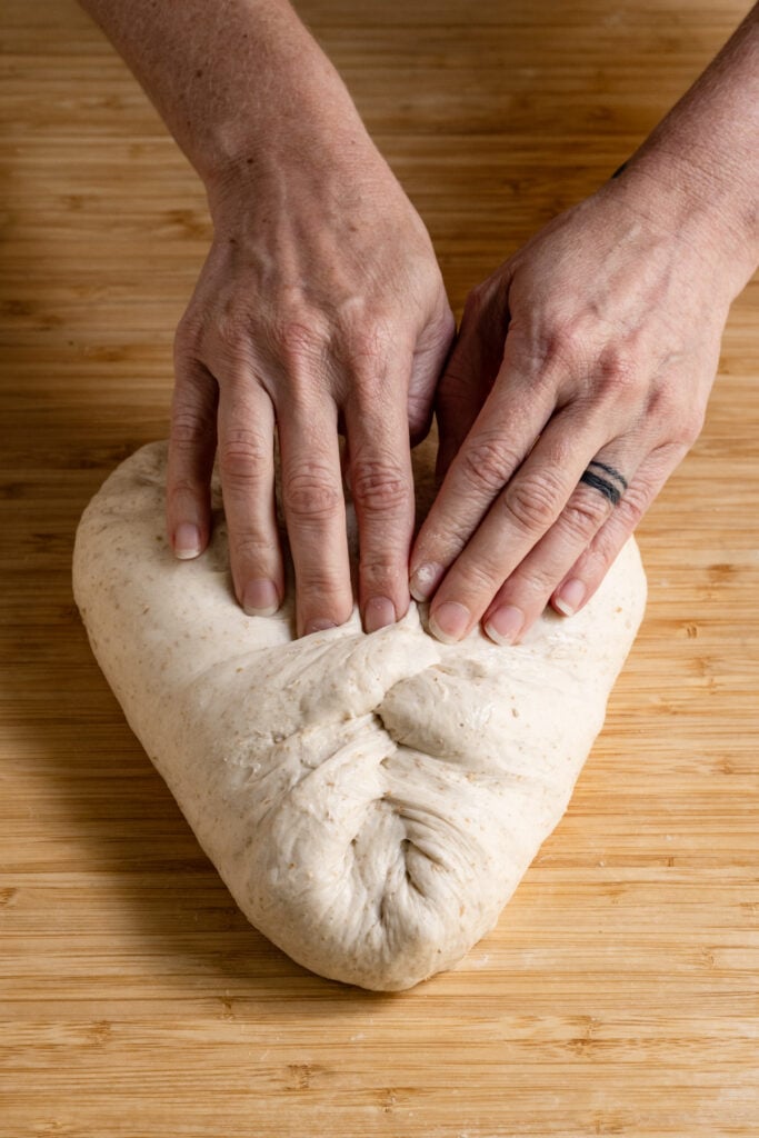 Hands shaping a loaf of sourdough.