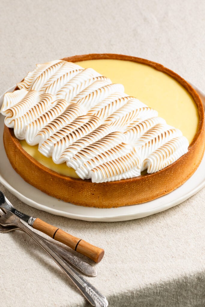 Lemon curd tart on a plate topped with toasted meringue.