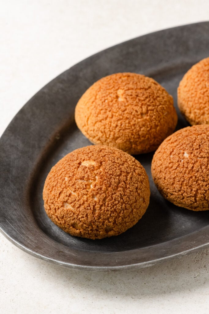 Baked craquelin choux pastry on an oval plate.