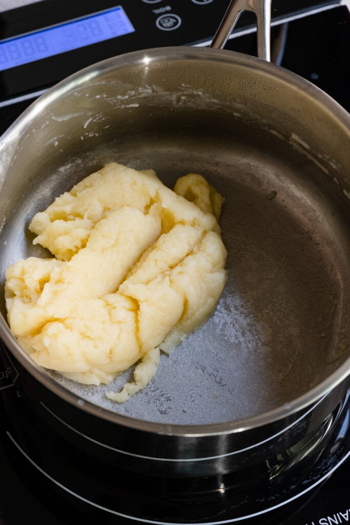 Choux pastry being cooked in a saucepan.