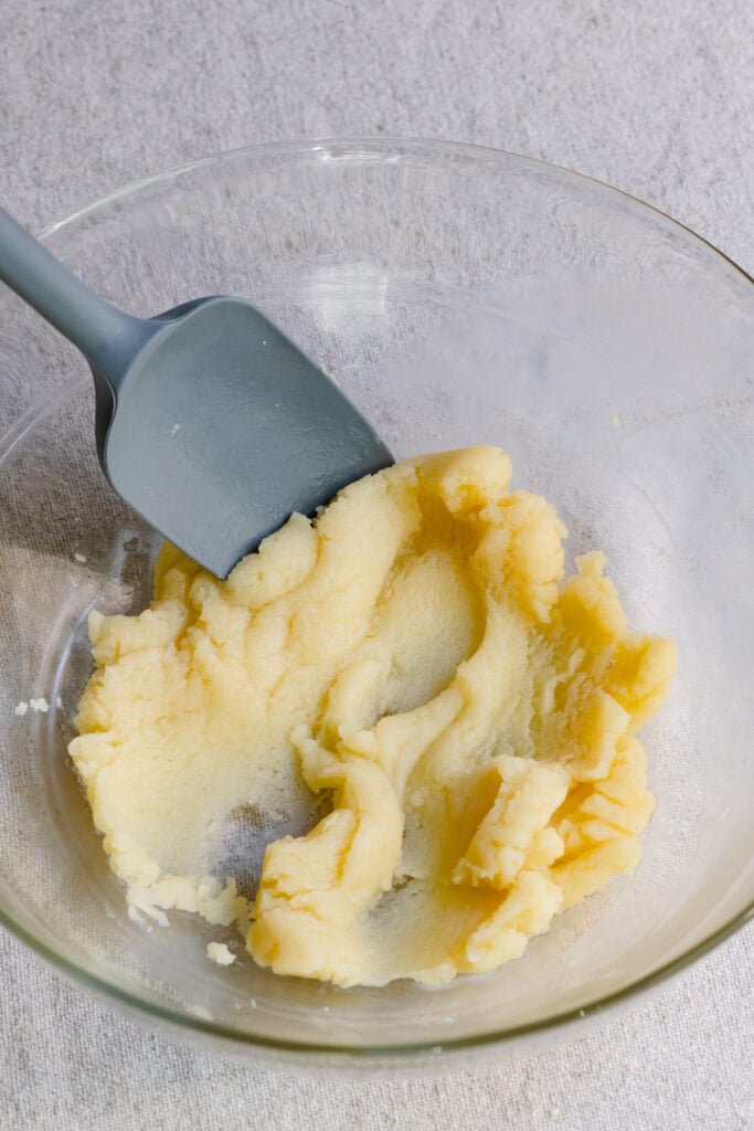 Choux pastry dough mashed in a bowl with a spatula.