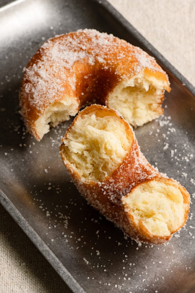 Donut coated in sugar and split in half on a serving tray.